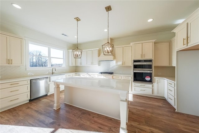 kitchen featuring pendant lighting, white cabinets, appliances with stainless steel finishes, a center island, and dark hardwood / wood-style floors