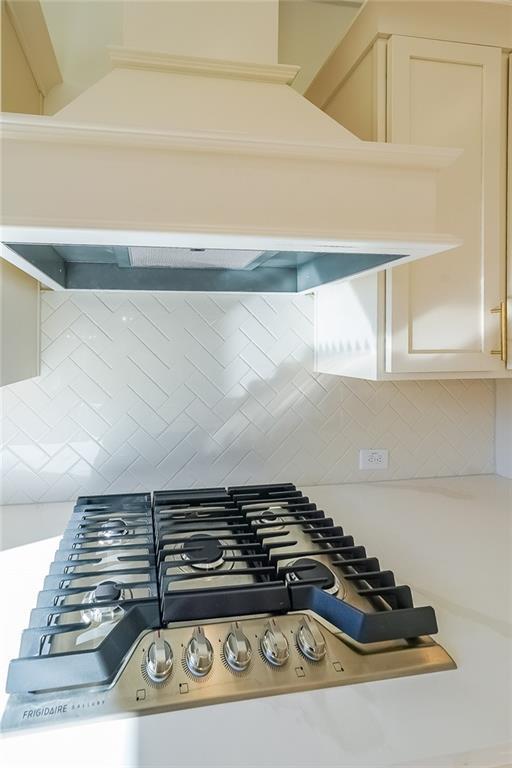 details with custom exhaust hood, decorative backsplash, and gas cooktop