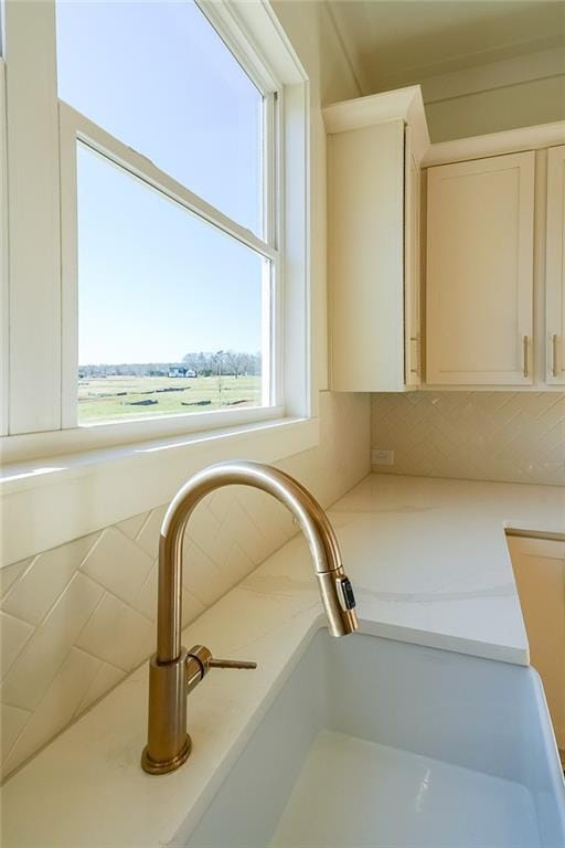 details featuring tasteful backsplash, sink, and white cabinetry