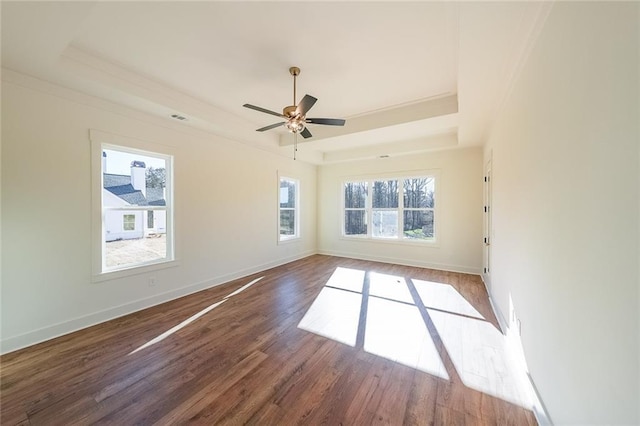 unfurnished room featuring ceiling fan, dark wood-type flooring, and a tray ceiling