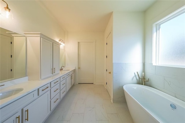 bathroom with a bathing tub, a wealth of natural light, tile walls, and vanity