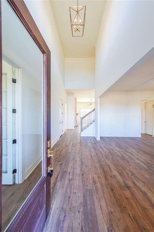 corridor with dark hardwood / wood-style flooring, an inviting chandelier, and a towering ceiling