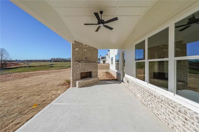 view of patio featuring an outdoor brick fireplace and ceiling fan