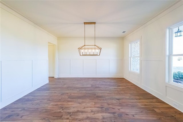 unfurnished dining area with ornamental molding, a chandelier, and dark hardwood / wood-style floors