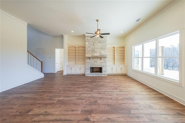 unfurnished living room featuring ornamental molding, plenty of natural light, and built in shelves