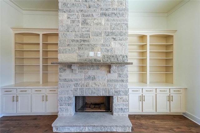 unfurnished living room featuring crown molding, dark hardwood / wood-style flooring, and a stone fireplace