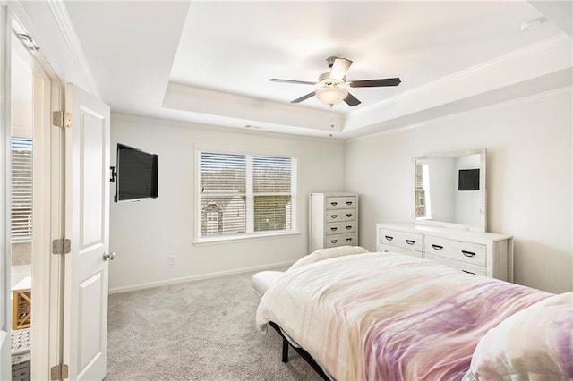 bedroom with ornamental molding, light colored carpet, ceiling fan, and a tray ceiling