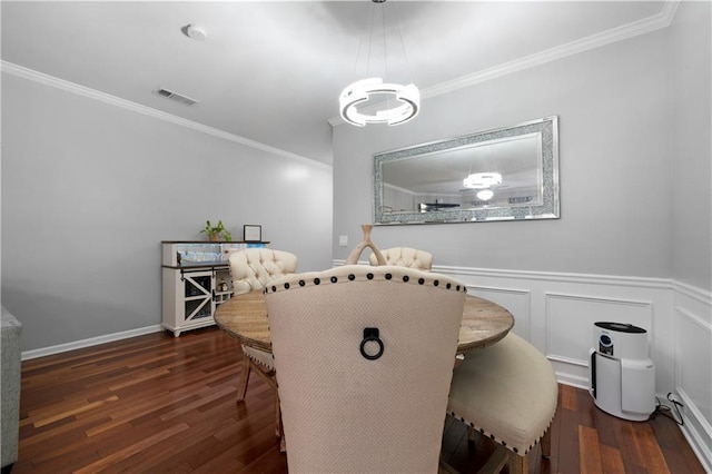 dining area featuring ornamental molding, wood finished floors, a chandelier, and wainscoting