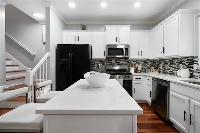kitchen with appliances with stainless steel finishes, a kitchen island, decorative backsplash, white cabinets, and recessed lighting
