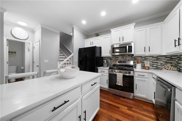 kitchen featuring stainless steel appliances, ornamental molding, tasteful backsplash, dark wood-style flooring, and white cabinets