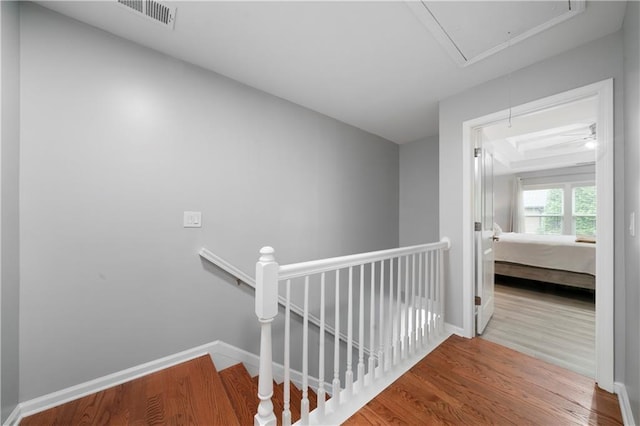 hall with attic access, an upstairs landing, wood finished floors, and baseboards