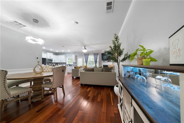 dining space featuring ornamental molding, a chandelier, dark wood-style floors, and a ceiling fan