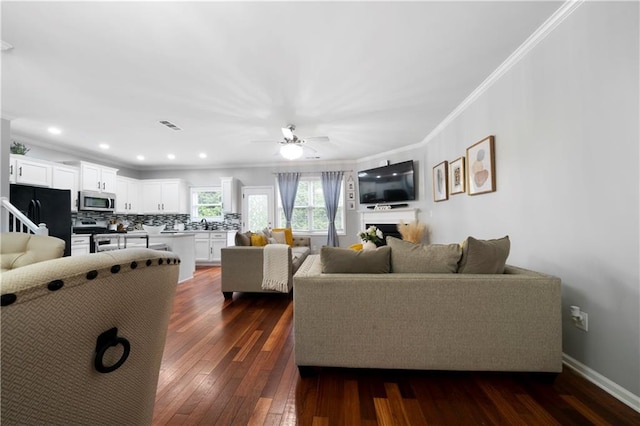 living room featuring crown molding, dark wood-style flooring, ceiling fan, baseboards, and recessed lighting