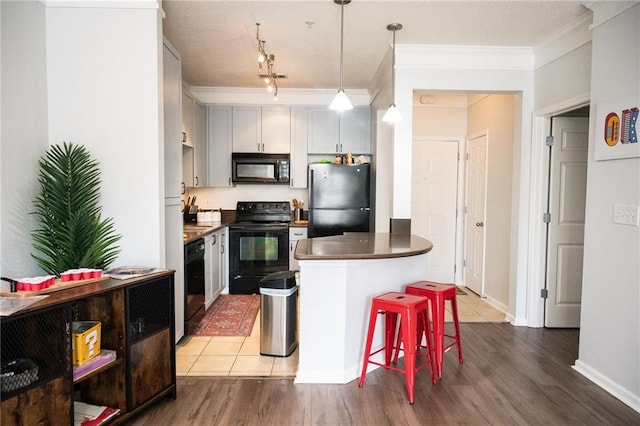 kitchen featuring track lighting, black appliances, hardwood / wood-style floors, gray cabinets, and crown molding