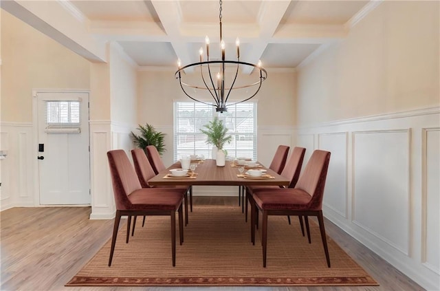 dining area with coffered ceiling, beam ceiling, a chandelier, wood finished floors, and a decorative wall