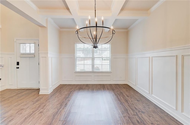 unfurnished dining area featuring a decorative wall, wood finished floors, an inviting chandelier, and beam ceiling