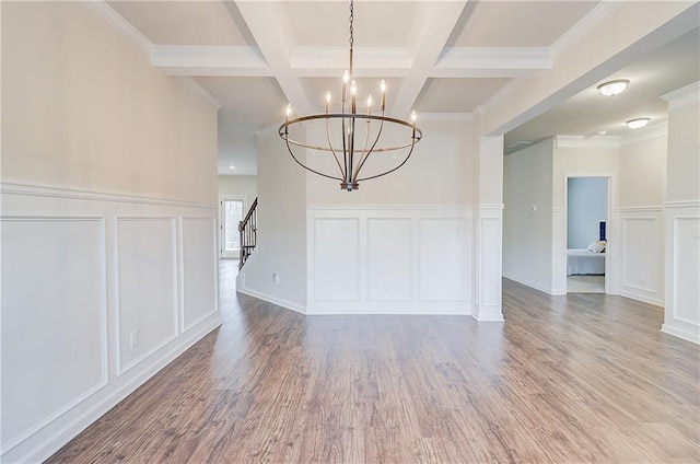 unfurnished dining area featuring stairs, an inviting chandelier, beam ceiling, a decorative wall, and wood finished floors