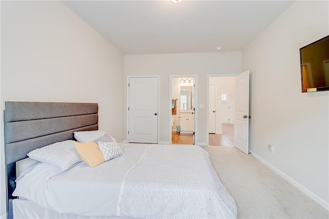 carpeted bedroom featuring baseboards and ensuite bathroom
