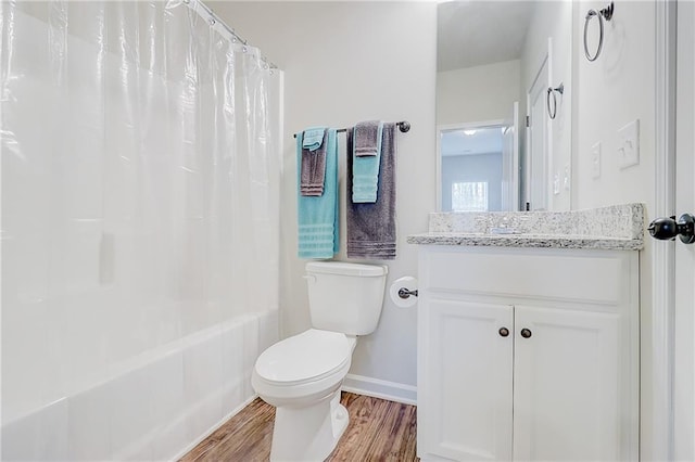 full bath with toilet, vanity, wood finished floors, shower / bath combo with shower curtain, and baseboards
