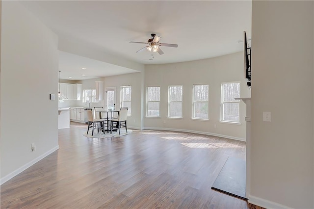 living room with a ceiling fan, baseboards, and wood finished floors