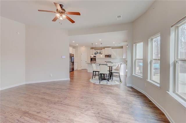 dining room with light wood-style flooring, baseboards, ceiling fan, and visible vents