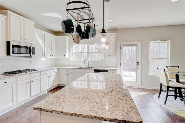 kitchen with a sink, light wood-type flooring, decorative backsplash, and appliances with stainless steel finishes
