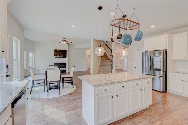 kitchen with white cabinets, a ceiling fan, stainless steel appliances, and light wood finished floors