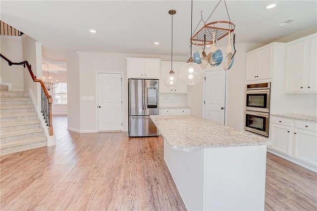 kitchen with recessed lighting, light wood-type flooring, a kitchen island, white cabinets, and appliances with stainless steel finishes
