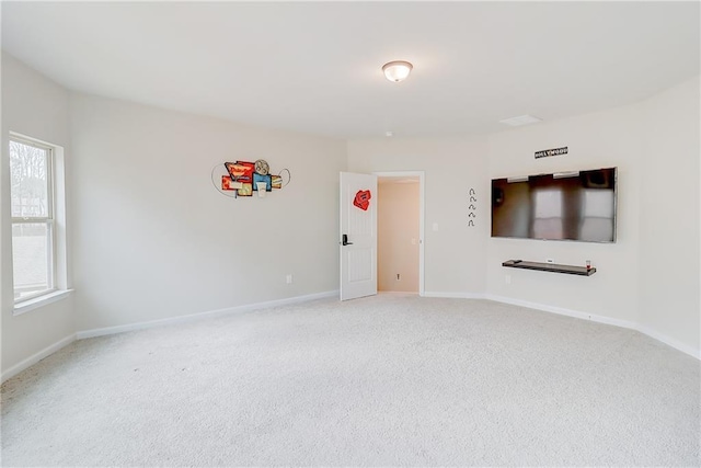 spare room with baseboards and light carpet