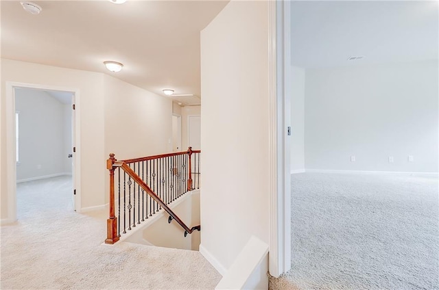 corridor featuring baseboards, carpet flooring, and an upstairs landing