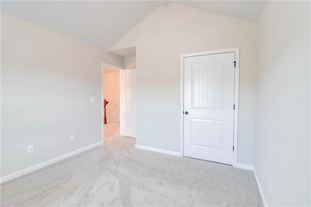 unfurnished bedroom with baseboards, lofted ceiling, and carpet