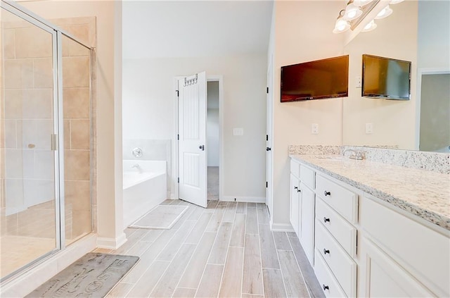 bathroom featuring vanity, a shower stall, a bath, baseboards, and wood tiled floor