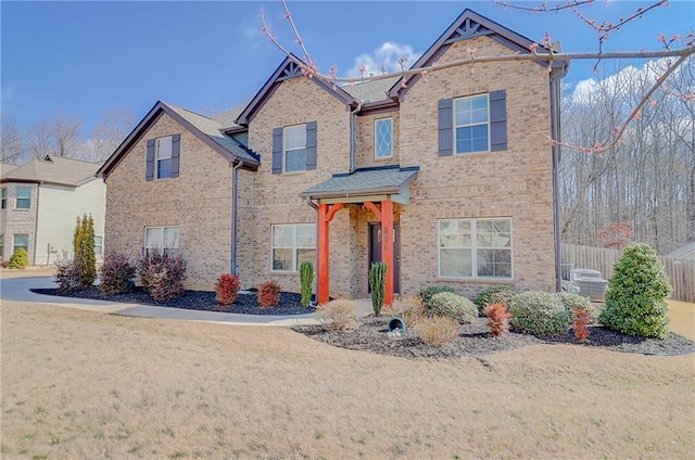 traditional-style house featuring brick siding, fence, and a front yard