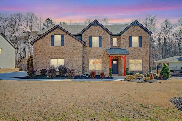 traditional-style home with brick siding and a lawn