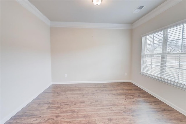 spare room with wood finished floors, crown molding, baseboards, and visible vents