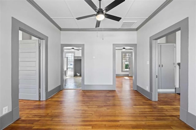 spare room featuring visible vents, plenty of natural light, baseboards, and wood finished floors