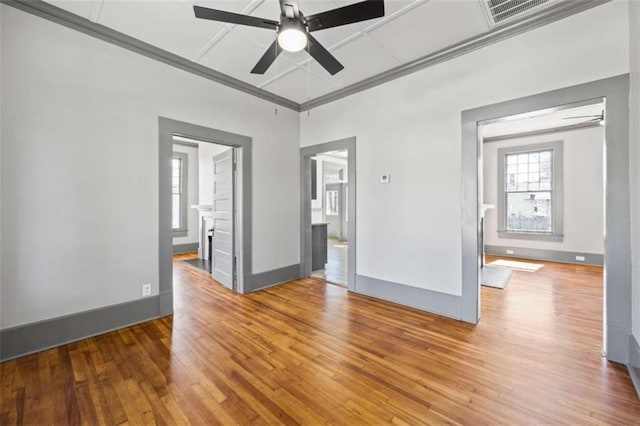 empty room with a ceiling fan, visible vents, baseboards, and wood finished floors