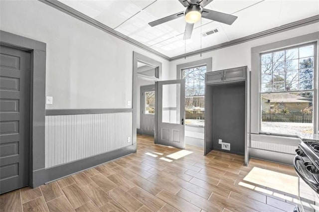 doorway to outside with ornamental molding, wood finish floors, wainscoting, and visible vents