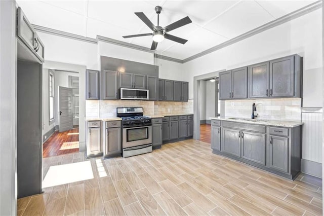 kitchen featuring stainless steel appliances, gray cabinets, backsplash, wood tiled floor, and a sink