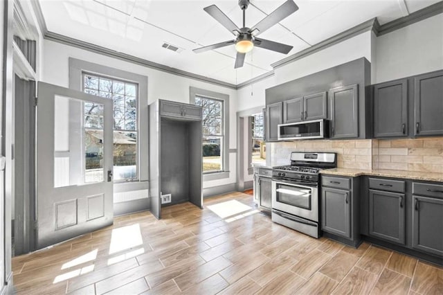 kitchen with appliances with stainless steel finishes, a wealth of natural light, visible vents, and decorative backsplash