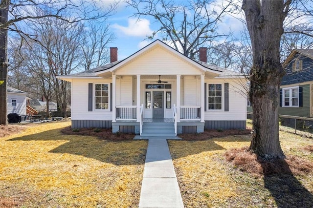 bungalow with covered porch, a chimney, and a front lawn