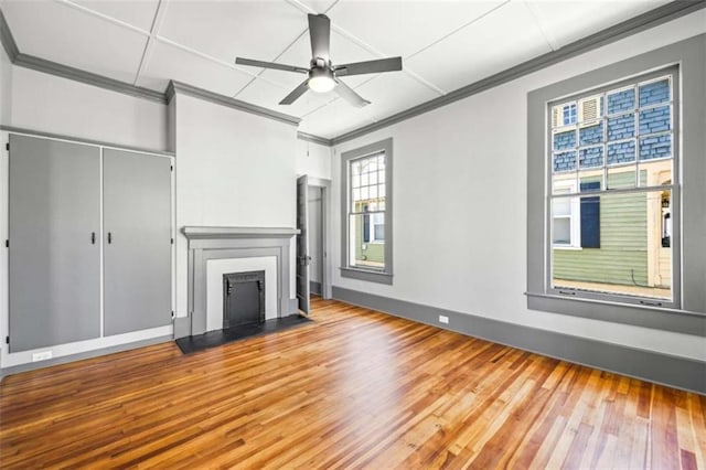 unfurnished living room featuring a fireplace with flush hearth, a ceiling fan, crown molding, and wood finished floors