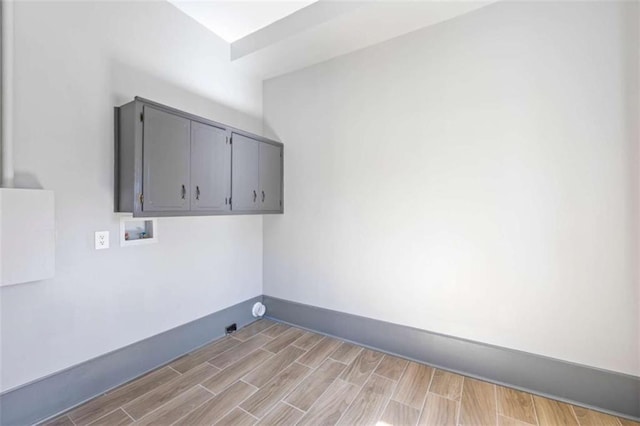 laundry area featuring hookup for a washing machine, wood tiled floor, cabinet space, and baseboards