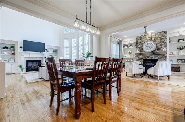 dining area featuring light wood-type flooring, built in features, and a fireplace