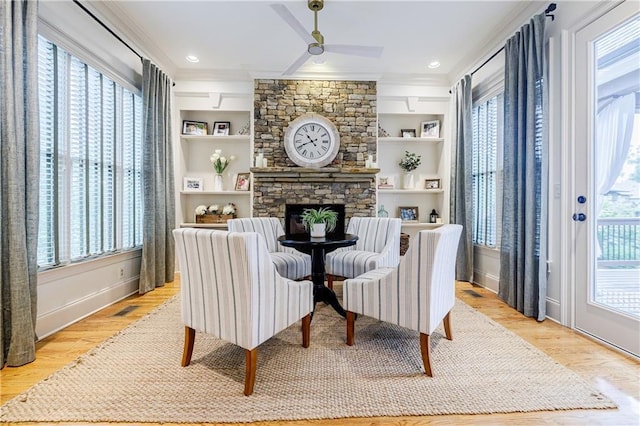 living area featuring built in features, a fireplace, and light hardwood / wood-style flooring