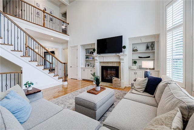 living room featuring built in shelves, light hardwood / wood-style floors, and a high ceiling