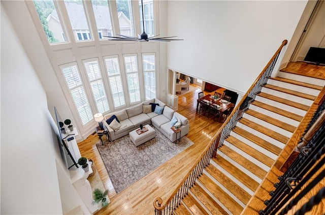 living room with a high ceiling, hardwood / wood-style flooring, and ceiling fan