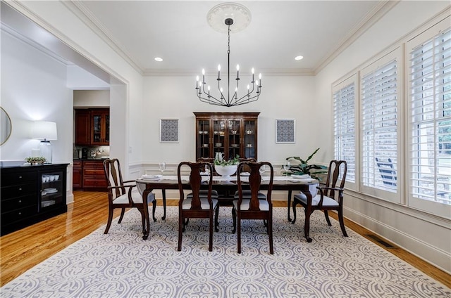 dining space featuring crown molding, light hardwood / wood-style flooring, and a chandelier