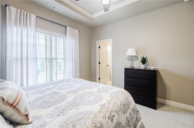 bedroom with a tray ceiling, ceiling fan, crown molding, and light carpet