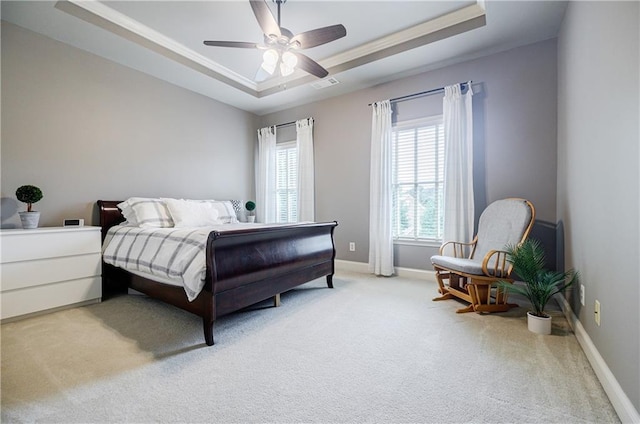 bedroom with a raised ceiling, ceiling fan, and light colored carpet